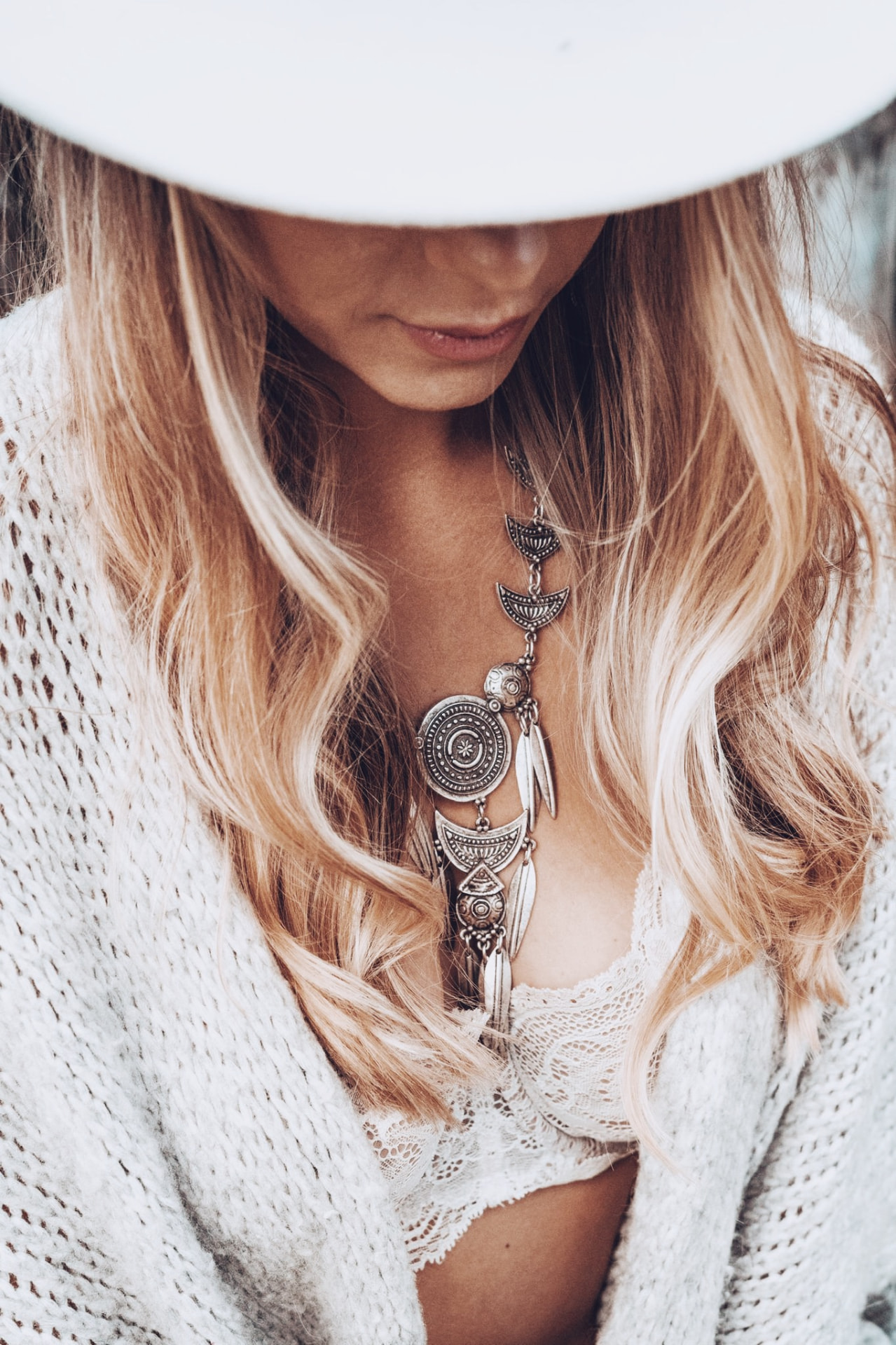 Erika in a wide-brim white hat and silver statement necklace