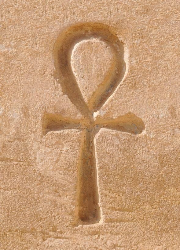 An ankh carved into a weathered sandstone wall